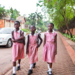 Three African girls walking in school uniforms